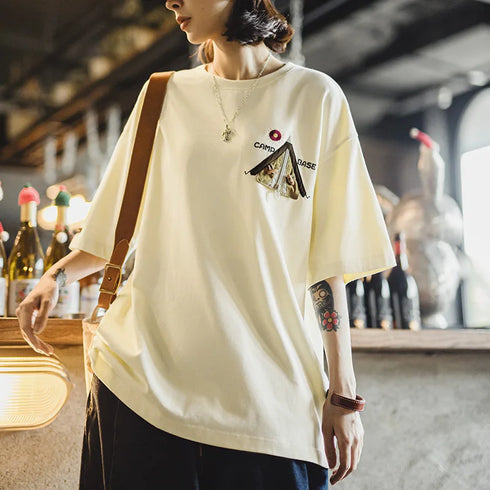 Person wearing a light yellow t-shirt with a graphic design in an indoor setting.